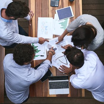 Laptop, meeting and above of business people with documents for financial planning, review and report. Corporate, office and workers with charts, graphs and paperwork for discussion and teamwork.